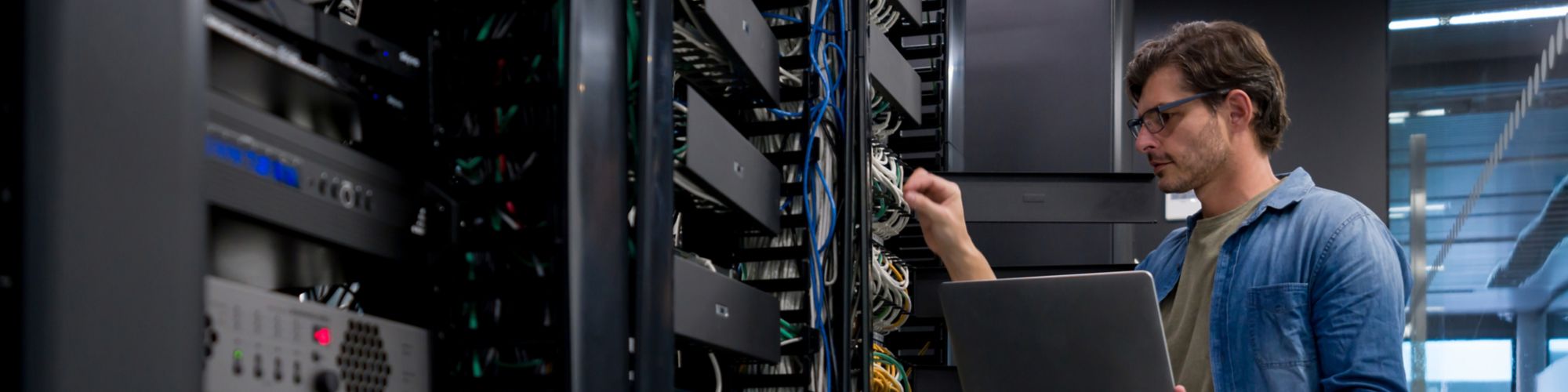 Técnico de soporte de TI que arregla un servidor de red en una oficina