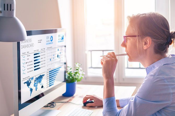 Businesswoman looking at business analytics (BA) or intelligence (BI) dashboard on the computer screen with sales data statistical report and key performance indicators (KPI)