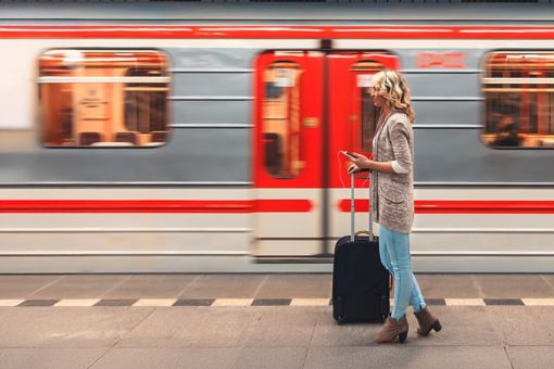 Lady holding suitcase standing outside moving train