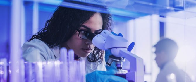 Woman using microscope in lab - Life sciences