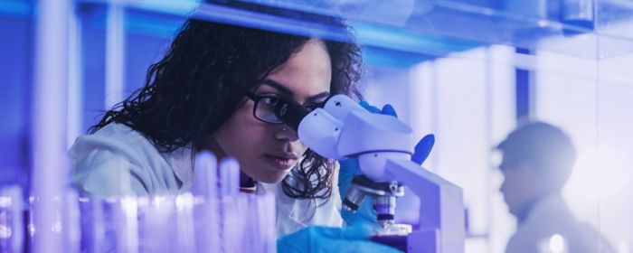 Woman using microscope in lab - Life sciences