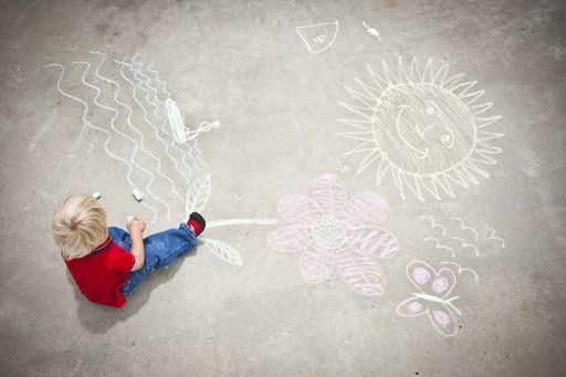Kleines Kind malt mit Kreide auf den Boden