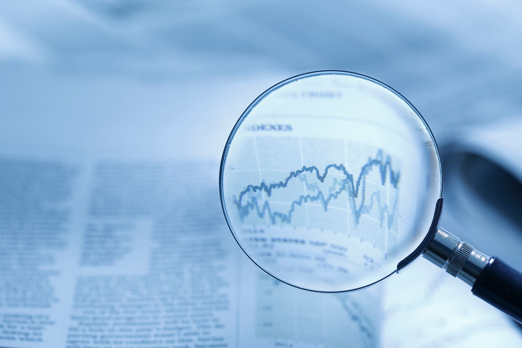 macnifying glass on newspaper line graph