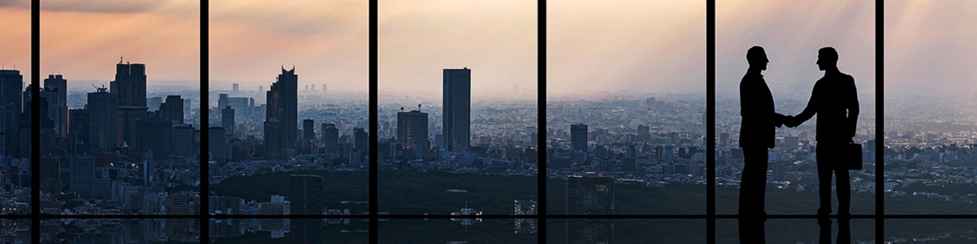 Männer schütteln Hände vor Skyline