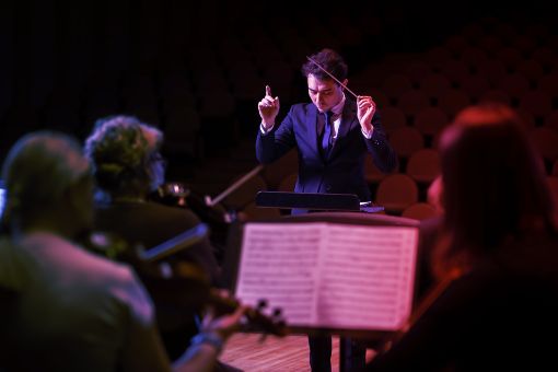 man conductor in front of orchestra