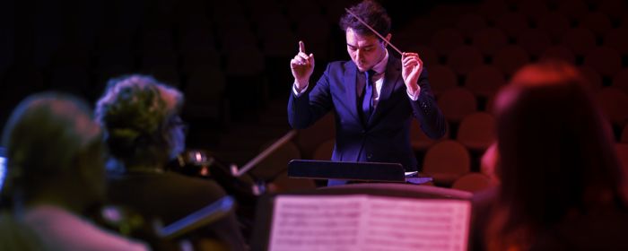 man conductor in front of orchestra