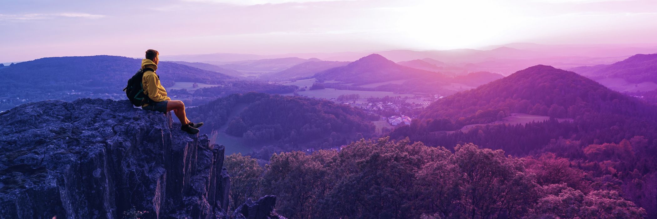 male hiker sitting on edge of rock