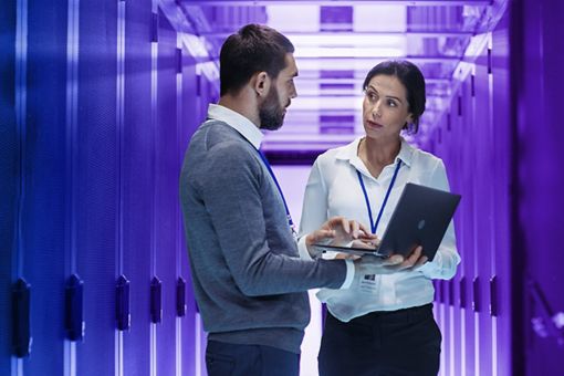 Man and woman looking at laptop in server room