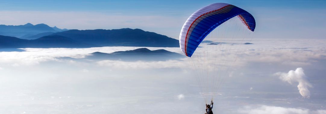 Man flying on parachute above clouds