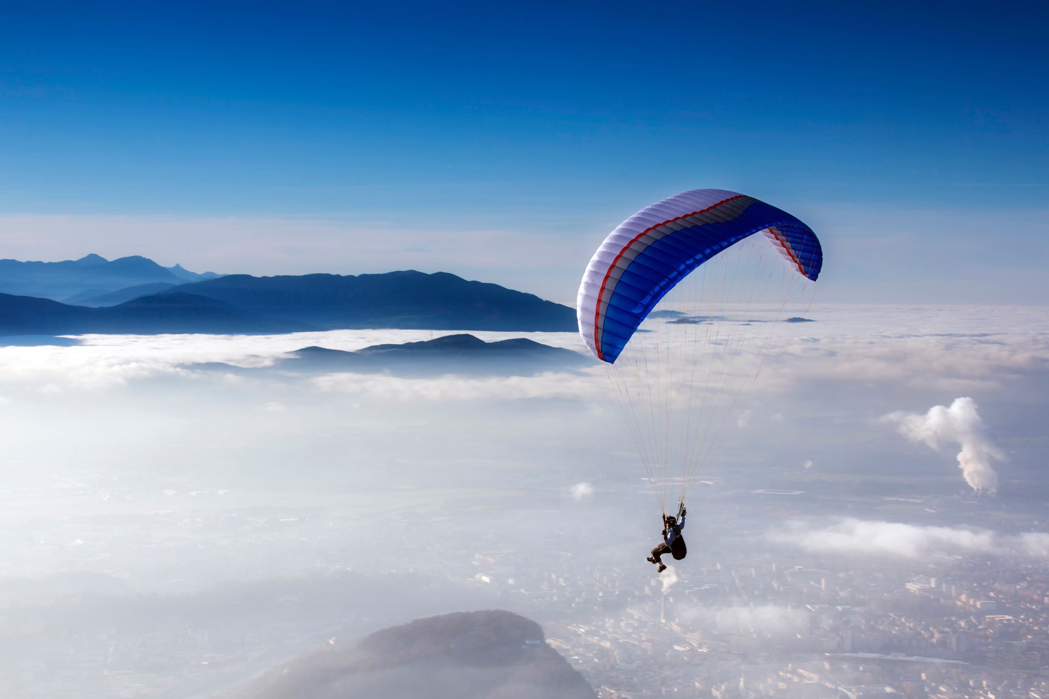 Man flying on parachute above the clouds