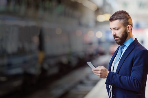 Man in train station platform looking at phone