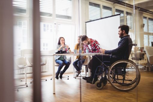 Man in wheelchair at table with colleagues