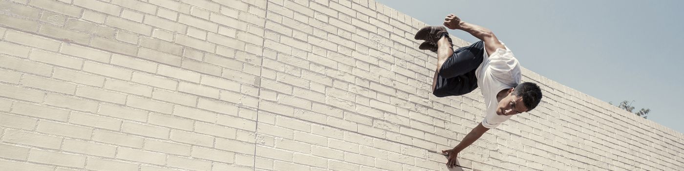 Man jumping forwards off a brick wall
