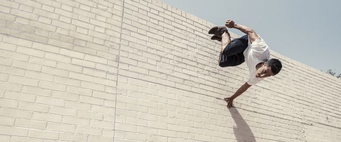 Man jumping forwards off a brick wall