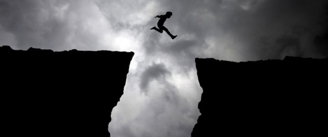 Man jumping from cliff amongst dark clouds