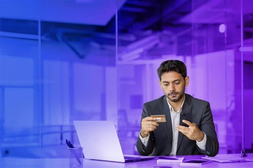 Man looking at phone and bank card