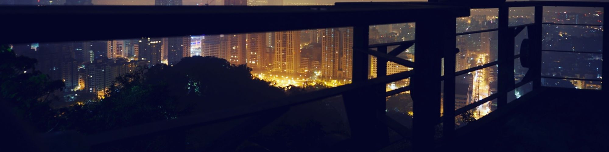 Man sitting on balcony railing and looking at city view