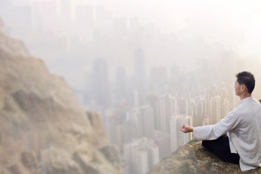 Man sitting on cliff yoga meditating