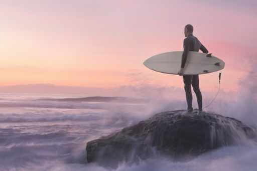 Man standing on cliff with surfboard