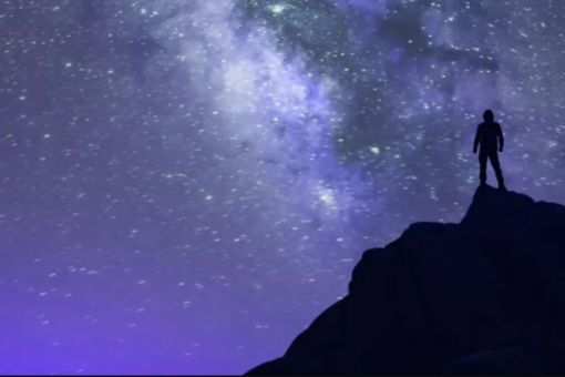 man standing on top of mountain looking at the galaxy