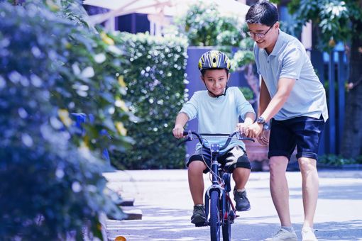 man teaching son to ride bicycle
