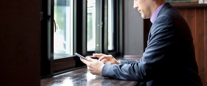 Man using cellphone sitting near window