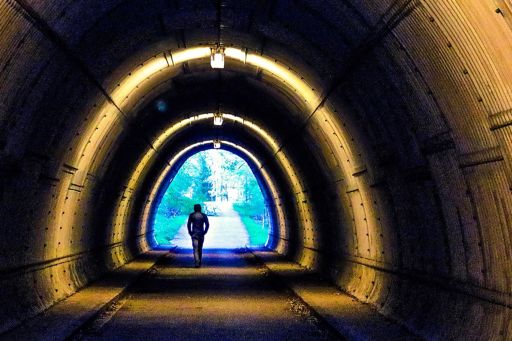 Man Walking In Illuminated Tunnel