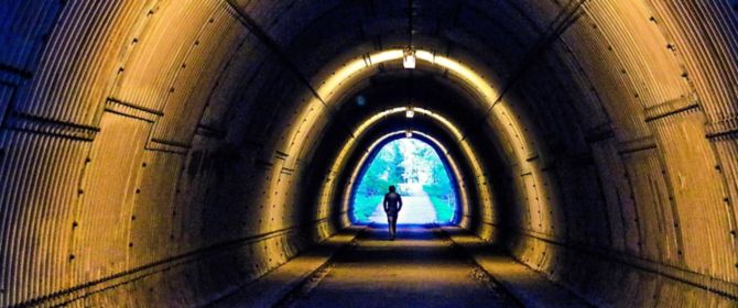 Man Walking In Illuminated Tunnel