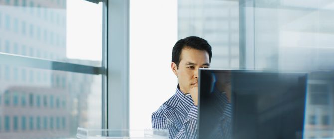 Businessman wearing check pattern shirt sitting in front of desktop