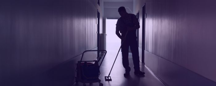 Man with broom sweeping an office corridor