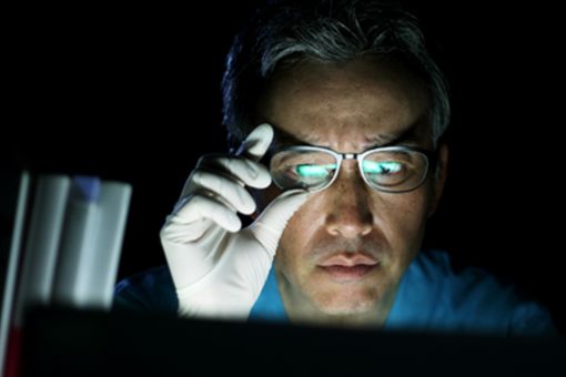 Man with gloves adjusting glasses looking at screen