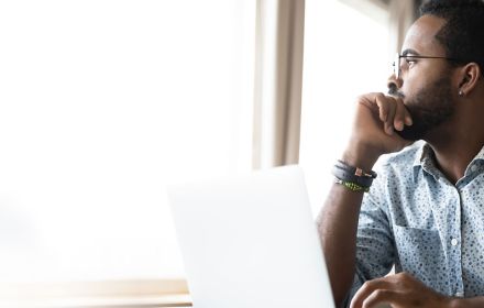 Man with laptop looking outside window
