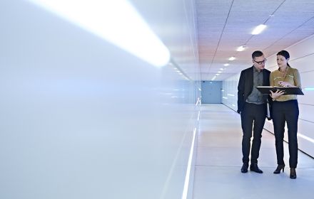 Businesspeople standing in an office corridor looking at a file