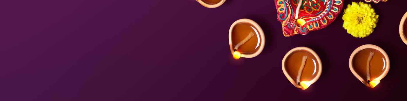 Many lit up diya and flowers against purple background