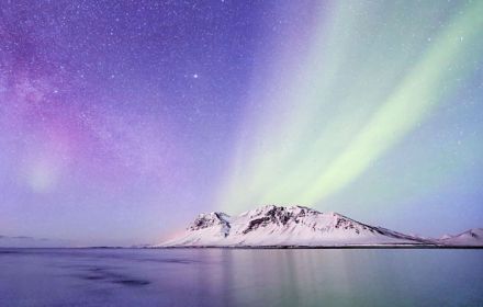Northern lights over a mountain with snow