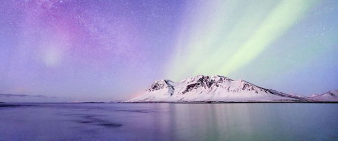 Northern lights over a mountain with snow