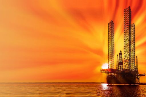 View of oil drilling rig during sunset in ocean