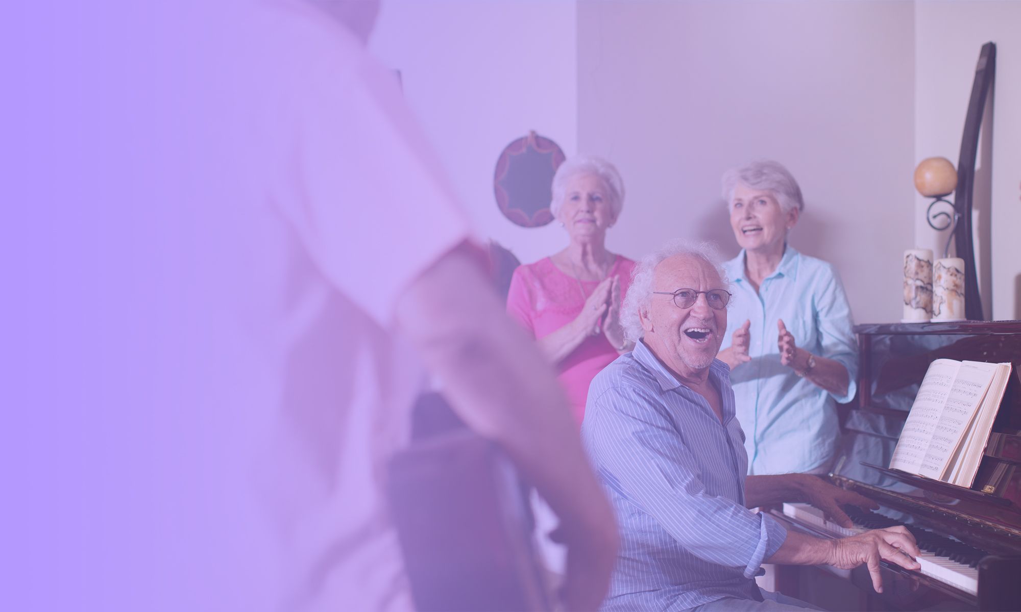 An older man plays a piano and sings in an aged care home