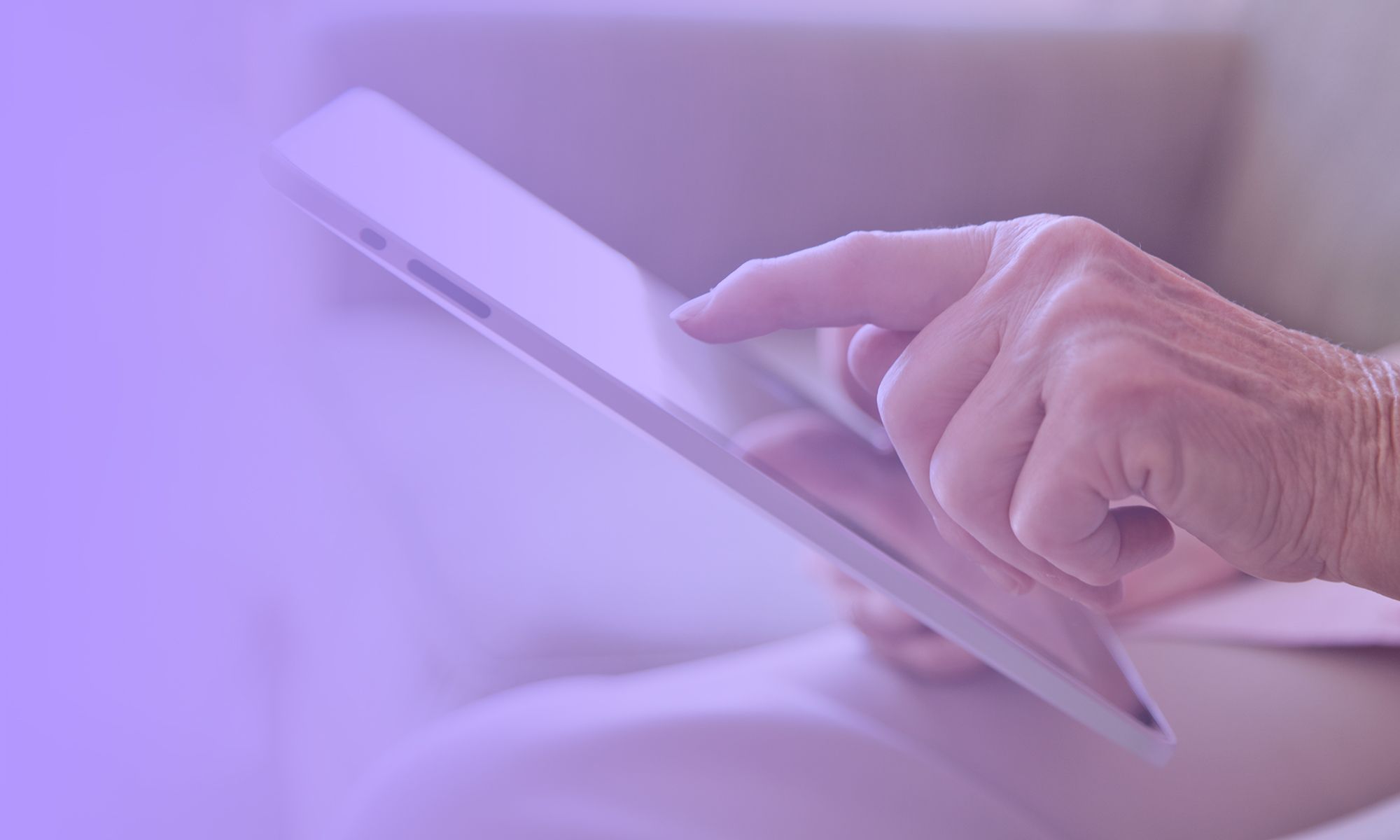 The hand of an elderly woman interacting with a tablet