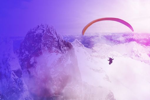Paraglider flying through mountain landscape