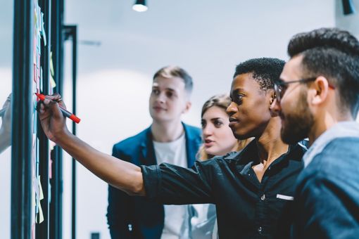 Des personnes collaborant devant un tableau blanc