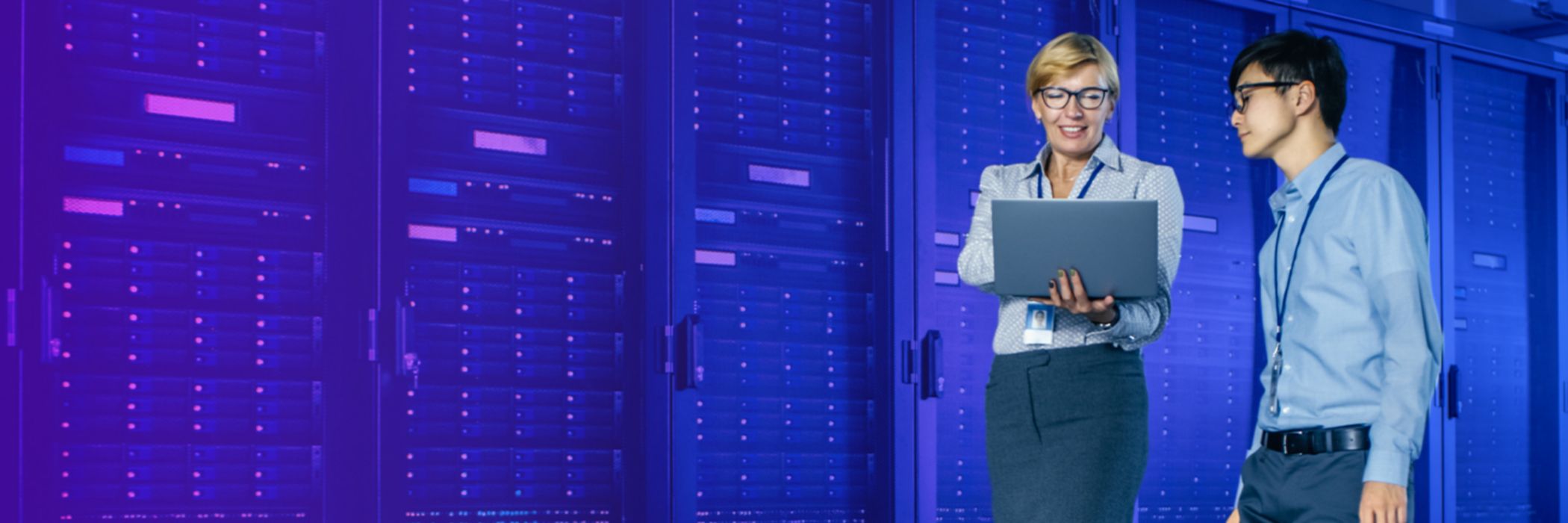 People walking whilst holding a laptop in a server room