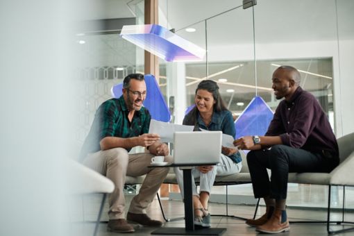 people sat on a table in discussion in an open plan office space