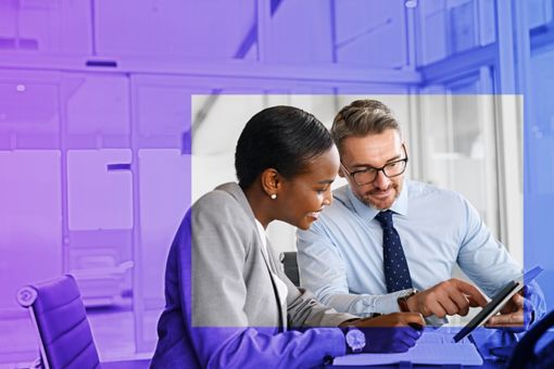 People sat at a desk in an office looking at a tablet