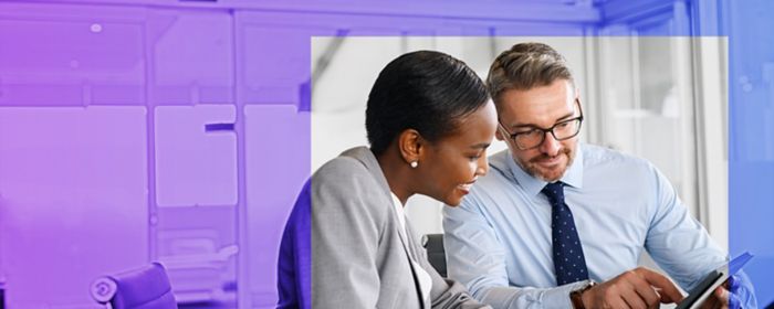 People sat at a desk in an office looking at a tablet