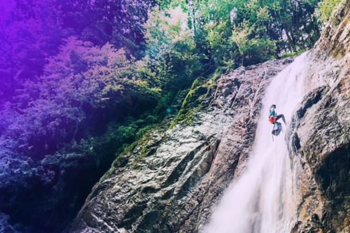 Person klettert neben Wasserfall an Berg