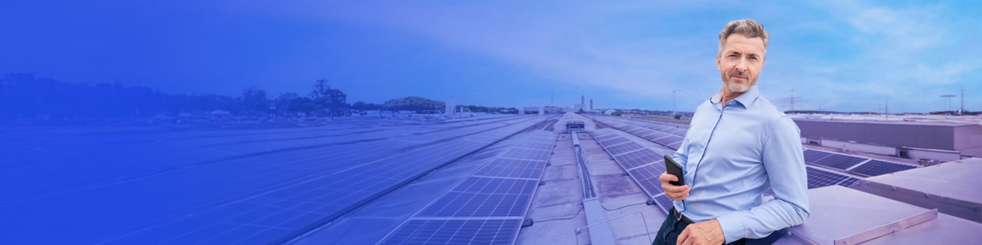 Person standing holding a phone with solar panels in the background