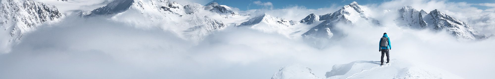 Person steht auf Berg umgeben von Wolken