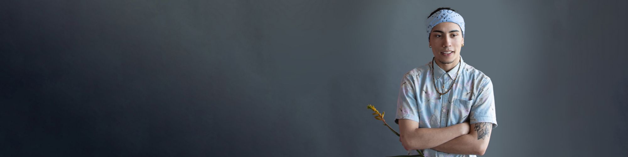 A young male student holding a flower on a grey background