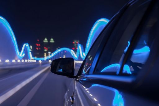 Rear view mirror of car on illuminated bridge at night